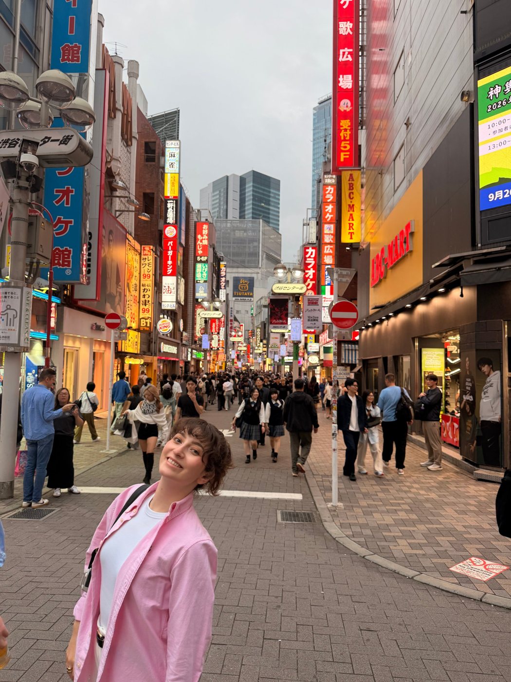 Nati sorrindo numa rua movimentada de Shibuya